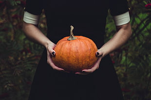 woman in black dress holding pumpkin
