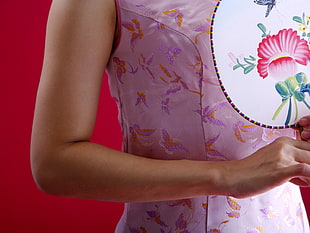 person in pink floral top holding floral fan