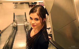 woman wearing black scoop-neck shirt standing on escalator