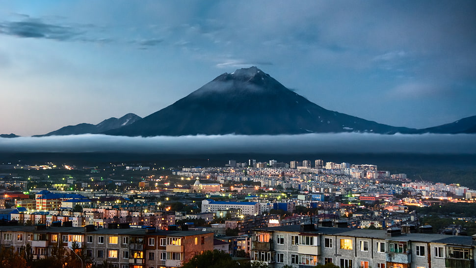 mountain across city under cloudy sky during dusk, kamchatka HD wallpaper
