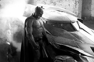 Batman standing near batmobile grayscale photo
