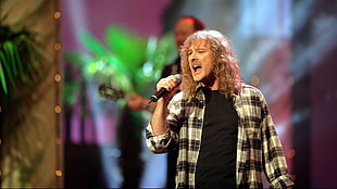 man wearing gray and black jacket holding microphone singing