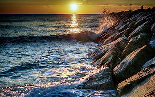 ocean waves near stone fragment during sunset