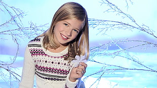 girl in white pink and black sweater holding snowflakes