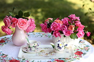 two pink petaled flowers arrangement with teapot and teacup on table