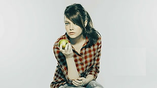 woman wearing black and white check sport shirt holding green apple