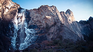 rock mountain with falls under blue sky
