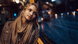 focus photo of woman in brown leather jacket leaning on window