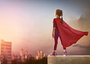 girl wearing red cape standing on ledge