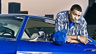 man in blue car wearing white and blue button collared shirt during daytime photo