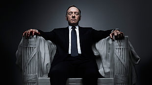 man in black suit sitting on white concrete armchair