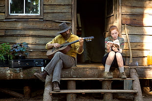 man playing guitar beside girl reading book