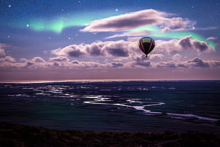 hot air balloon flying above body of water during nighttime HD wallpaper