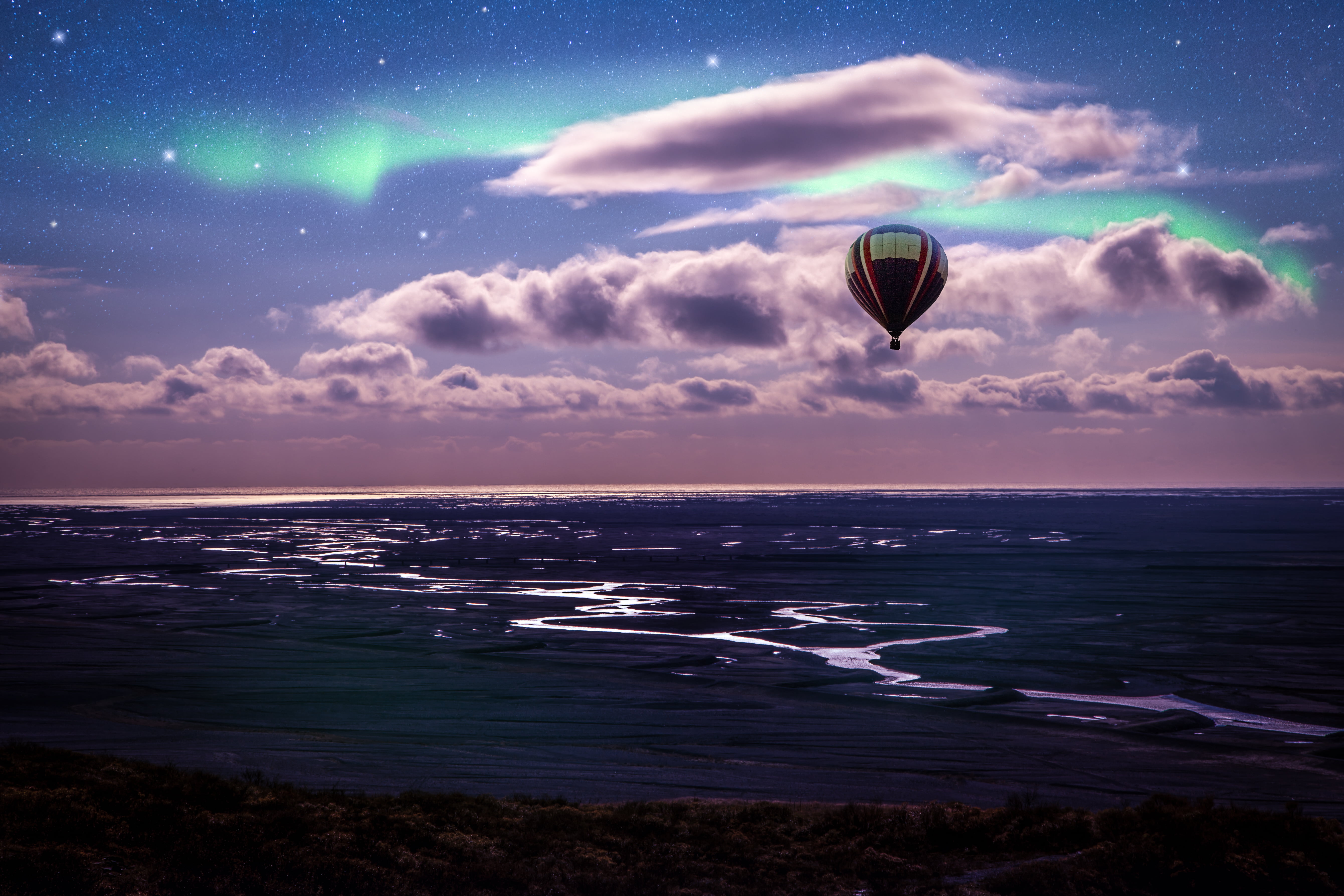 hot air balloon flying above body of water during nighttime