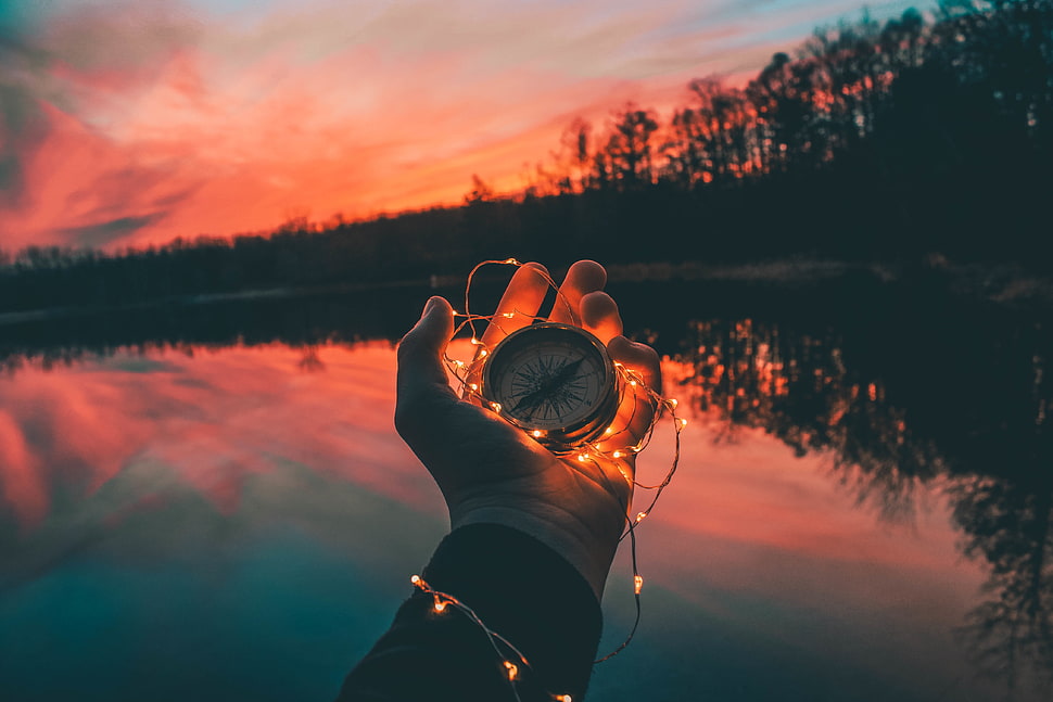 person holding yellow string lights and compass HD wallpaper
