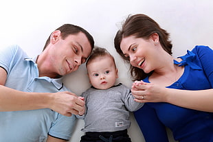 father and mother touching the hand of baby  and smiling
