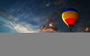 blue, yellow, and red hot air balloon photo durng sunset