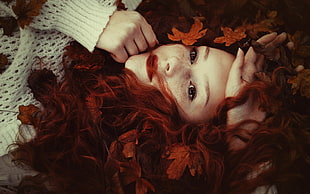 woman with red haired lying on brown leaves