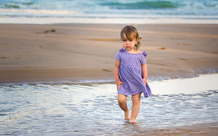 girl wearing purpler dress walking beside the beach