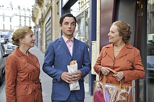 man in blue suit standing in between two women during daytime