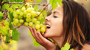 selective focus photography of a woman eating white grapes