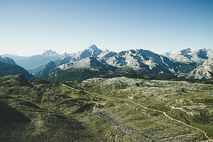 aerial photography of green field near snow covered mountains