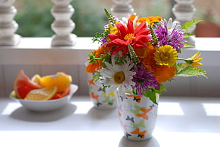 red , white and yellow flower arrangement in white ceramic vase