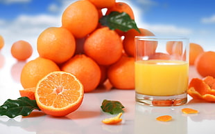 orange fruits beside clear drinking glass orange juice inside