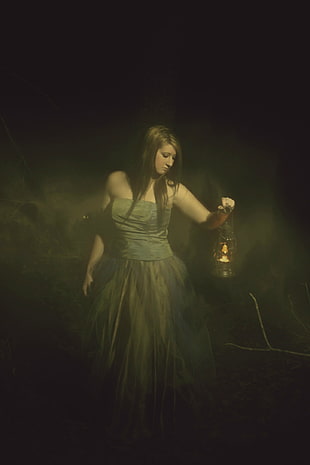 woman wearing gray strapless dress holding lantern