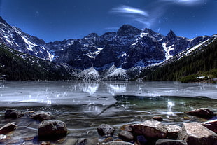 body of water near mountains during nighttime