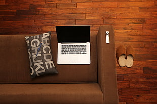 MacBook Pro on sofa beside pillow inside room
