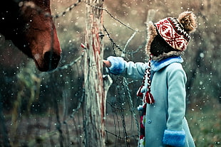 boy playing outside beside horse
