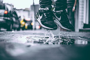 shallow photo of a man wearing a pair of Nike Air Max jumping on a wet street