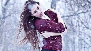 selective focus photography of woman in red sweater in middle of snow covered forest