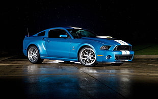 photo of blue and white Ford Shelby GT on concrete pavement with black background