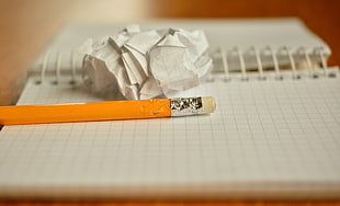 orange pencil with white lined paper