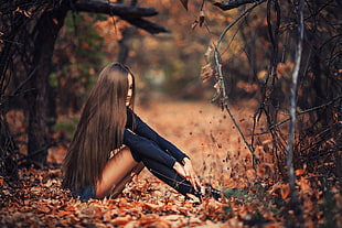 woman sitting on brown dried leaves taken during daytime