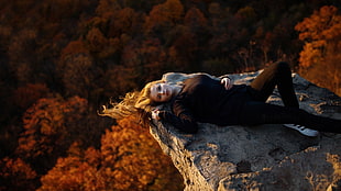 woman in black shirt laying on rocky mountain HD wallpaper