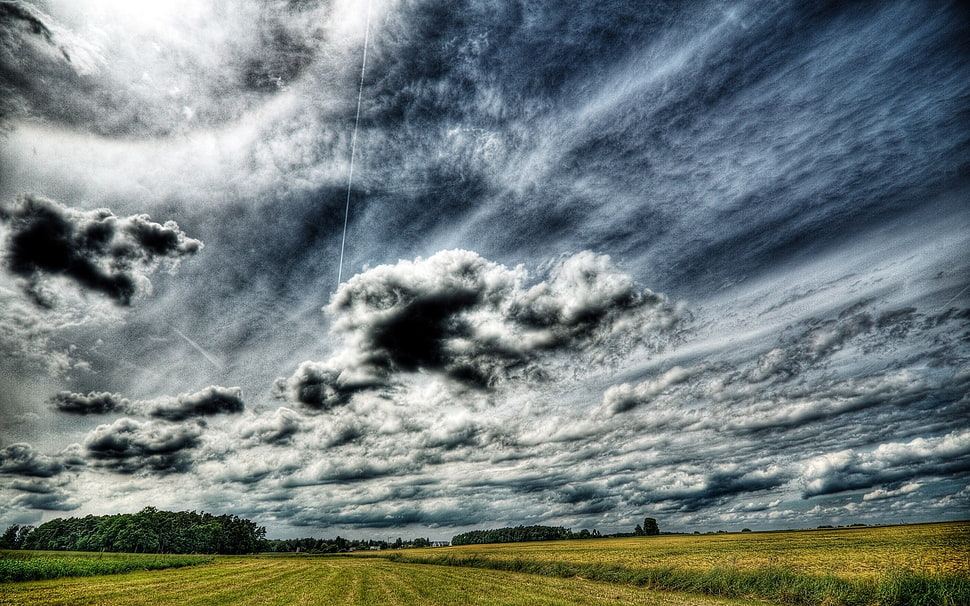 green field under dark clouds HD wallpaper