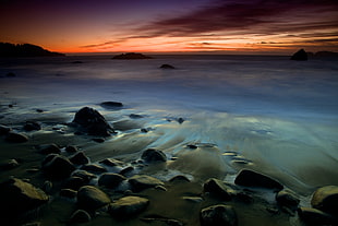 rocks on seashore during sunset