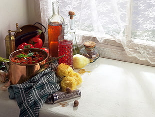 glass bottles near brown steel pot near window with white floral curtain