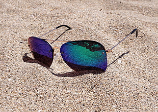 silver framed aviator sunglasses on top of brown sand