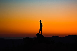 silhouette of man on top of rock formation