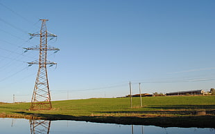 transmission tower near body of water with grass field HD wallpaper