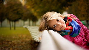 depth of field photo of woman sitting on adirondack bench