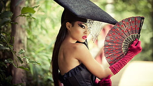woman wearing black strapless dress holding red hand fan