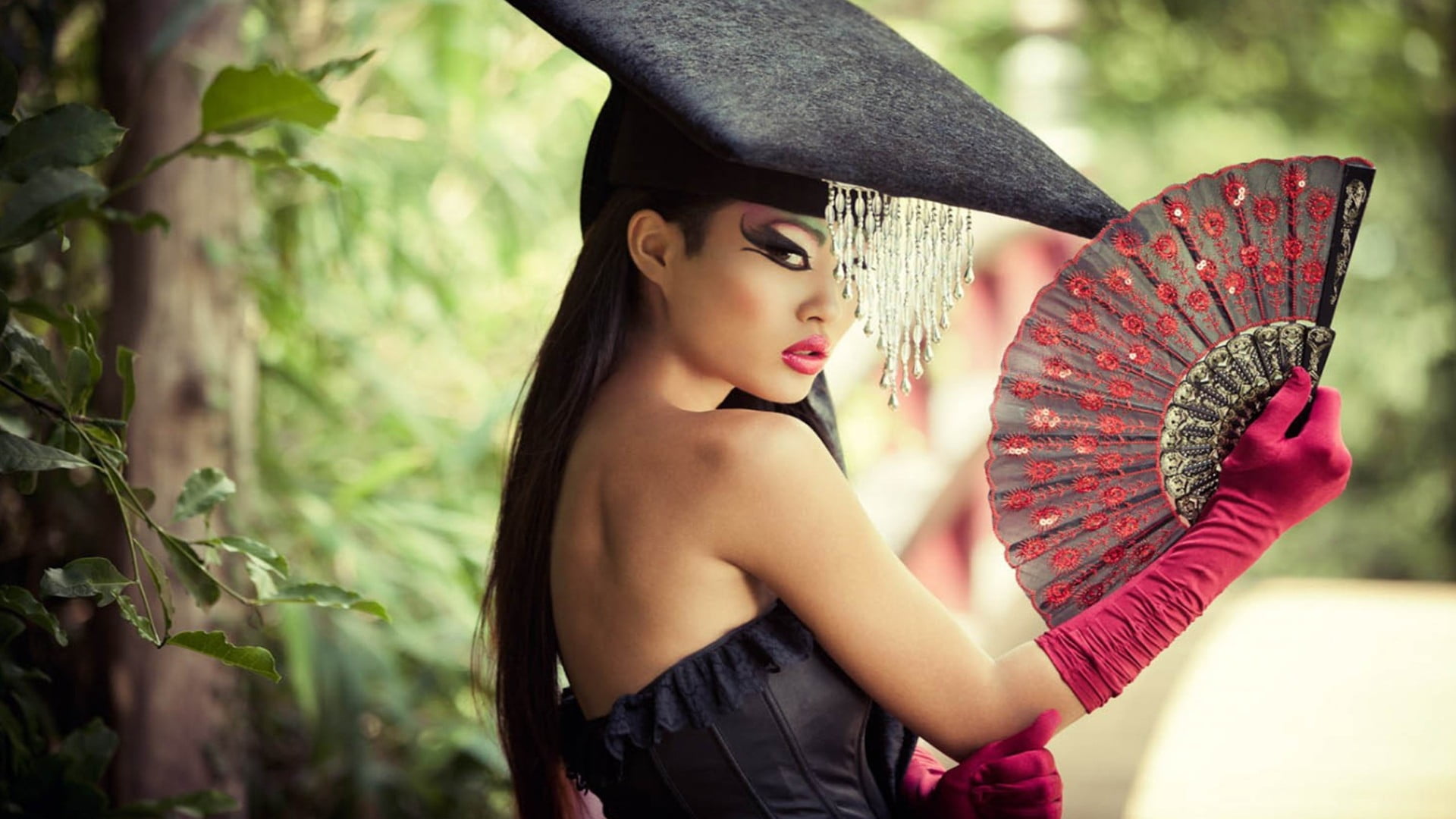 woman wearing black strapless dress holding red hand fan