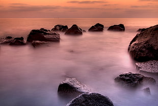 time-lapse photo of rocks beside the body of water HD wallpaper
