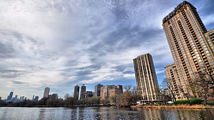 worm's eye view photography of buildings beside lake under cloudy sky during daytime
