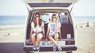 two women sitting on van